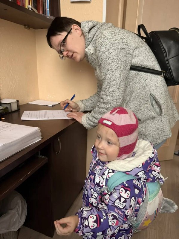 Ольга подписывает документы, рядом её ребёнок